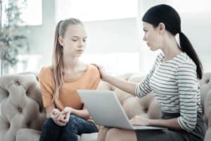 woman and teen on couch with laptop discussing mental health resources for teens