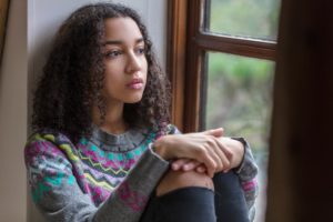 girl in sweater by window considering suicide rates in teens