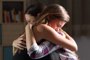 Woman wonders, "How do you learn how to help your teen with anxiety?" as she embraces her child