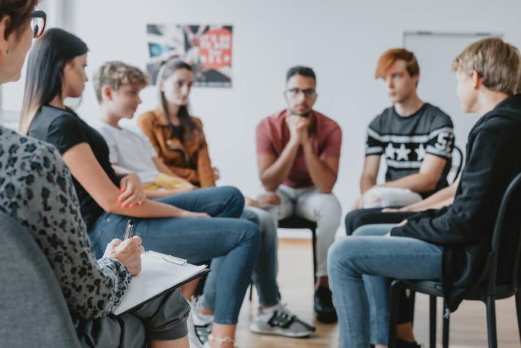 People sitting in a circle and talking about the benefits of interventions for teens